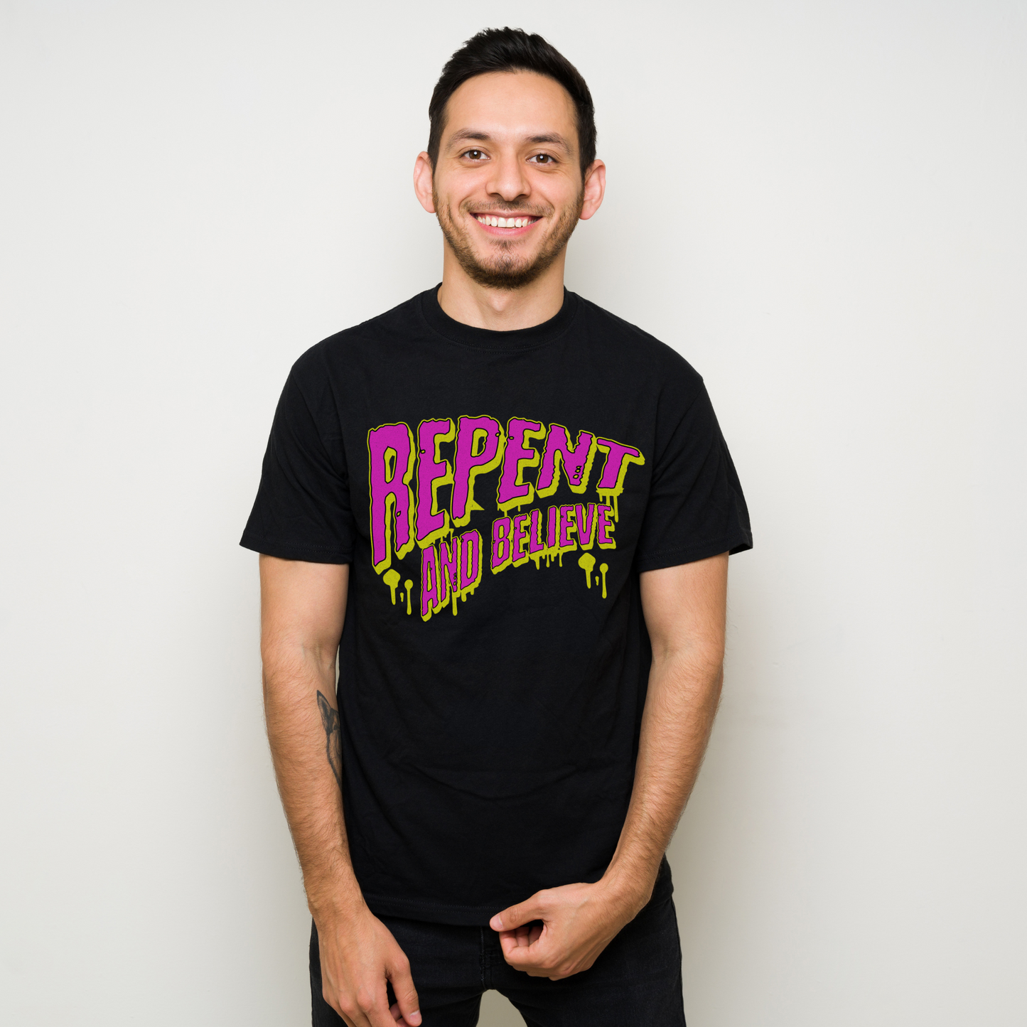 a man wearing a black crew neck short sleeve modern christian apparel graphic tee that says repent and believe